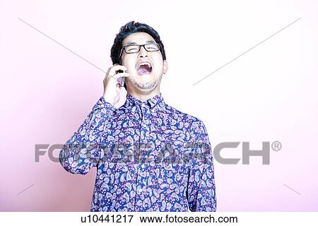 Young Geeky Asian Man in colorful shirt laughing on the phone View Large Photo Image Stock Photo - Young Geeky Asian Man in colorful shirt laughing on the phone. Fotosearch