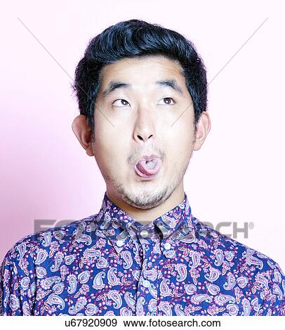 Stock Photo - Young Geeky Asian Man in colorful shirt pulling funny face. Fotosearch