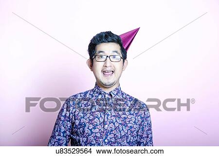 Picture - Young Geeky Asian Man wearing party hat. Fotosearch