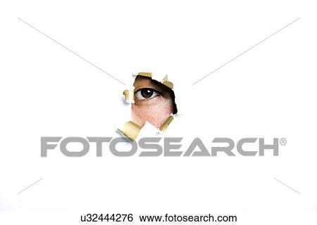 Stock Photograph - Young Korean man looking through ripped paper hole. Fotosearch