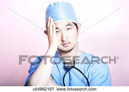 Young tired Asian surgeon wearing scrubs and looking stressed View Large Photo Image Stock Photo - Young tired Asian surgeon wearing scrubs and looking stressed. Fotosearch