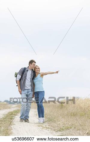 Young woman showing something to man while standing on trail at field View Large Photo Image Stock Photo - Young woman showing something to man while standing on trail at field. Fotosearch