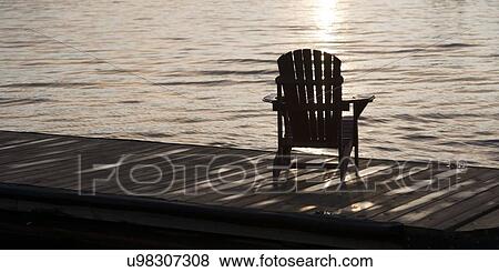 Adirondack chair on a dock at dawn, Lake Of The Woods, Keewatin, Ontario, Canada View Large Photo Image Stock Photo - Adirondack chair on a dock at dawn, Lake Of The Woods, Keewatin, Ontario, Canada. Fotosearch