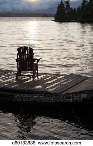 Adirondack chair on a dock at the Lake of The Woods, Keewatin, Ontario, Canada View Large Photo Image Stock Photograph - Adirondack chair on a dock at the Lake of The Woods, Keewatin, Ontario, Canada. Fotosearch