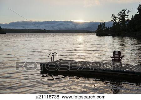 Adirondack chair on dock at lake, Lake Of The Woods, Keewatin, Ontario, Canada View Large Photo Image Stock Photo - Adirondack chair on dock at lake, Lake Of The Woods, Keewatin, Ontario, Canada. Fotosearch