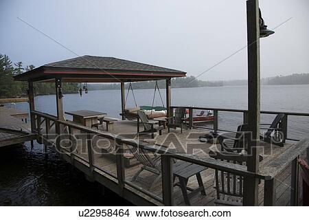 Picture - Adirondack chairs on a dock at Lake Of The Woods, Keewatin, Ontario, Canada. Fotosearch