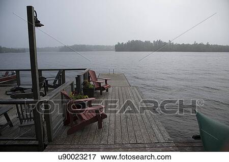 Adirondack chairs on a dock at Lake Of The Woods, Keewatin, Ontario, Canada View Large Photo Image Stock Photo - Adirondack chairs on a dock at Lake Of The Woods, Keewatin, Ontario, Canada. Fotosearch
