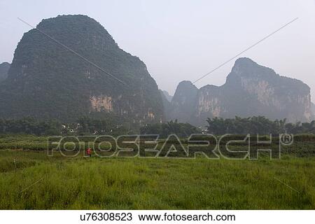 Stock Image - Agricultural field with mountains in the background, Yangshuo, Guilin, Guangxi Province, China. Fotosearch