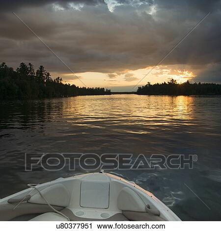 Stock Image - Boat on the lake at sunset, Lake of The Woods, Ontario, Canada. Fotosearch