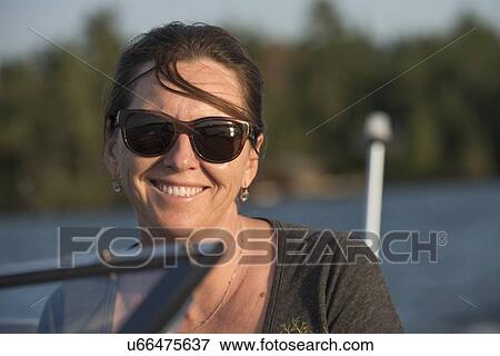 Stock Photo - Close-up of a woman smiling on a motorboat, Lake of The Woods, Keewatin, Ontario, Canada. Fotosearch