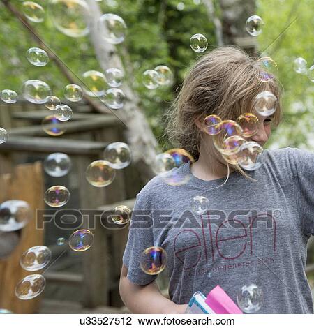 Stock Image - Close-up of a woman smiling while surrounded by bubbles, Lake of The Woods, Keewatin, Ontario, Canada. Fotosearch