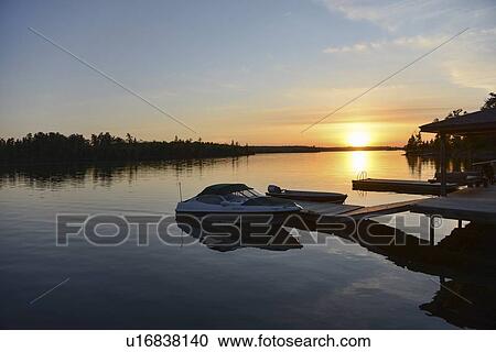 Stock Image - Dock in the Lake of The Woods at sunset, Keewatin, Ontario, Canada. Fotosearch