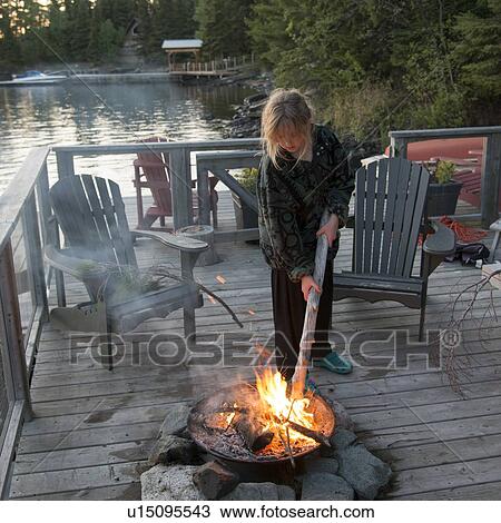 Stock Image - Girl enjoying a campfire, Lake of The Woods, Keewatin, Ontario, Canada. Fotosearch