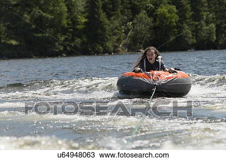 Stock Image - Girl enjoying on an inflatable raft, Lake of The Woods, Keewatin, Ontario, Canada. Fotosearch