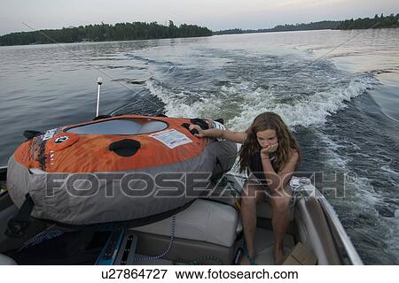 Stock Photo - Girl sitting on the edge of a boat and thinking, Lake of The Woods, Ontario, Canada. Fotosearch