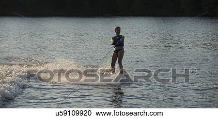 Stock Image - Girl waterskiing in a lake, Lake of The Woods, Keewatin, Ontario, Canada. Fotosearch
