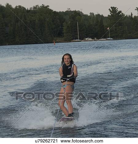 Stock Image - Girl waterskiing in a lake, Lake of The Woods, Keewatin, Ontario, Canada. Fotosearch