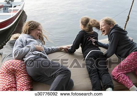 Stock Image - Girls enjoying on a swing at the lakeside, Lake of The Woods, Keewatin, Ontario, Canada. Fotosearch