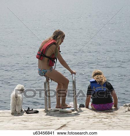 Girls sitting on a jetty at the lakeside, Lake of The Woods, Keewatin, Ontario, Canada View Large Photo Image Stock Image - Girls sitting on a jetty at the lakeside, Lake of The Woods, Keewatin, Ontario, Canada. Fotosearch