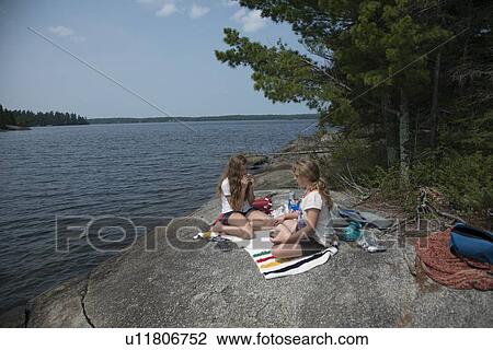 Girls sitting on the rock at the lakeside, Lake of The Woods, Kenora, Unorganized Kenora, Ontario, Canada View Large Photo Image Stock Image - Girls sitting on the rock at the lakeside, Lake of The Woods, Kenora, Unorganized Kenora, Ontario, Canada. Fotosearch