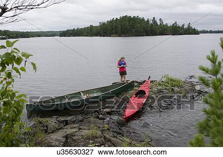 Stock Photo - Girls standing at the lakeside, Lake of The Woods, Keewatin, Ontario, Canada. Fotosearch