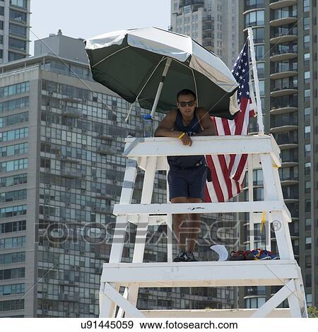 Stock Photo - Lifeguard standing on a lifeguard's tower, Chicago, Cook County, Illinois, USA. Fotosearch
