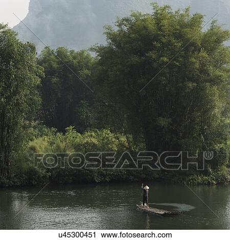 Man on raft on the Yulong River, Yangshuo, Guilin, Guangxi Province, China View Large Photo Image Stock Image - Man on raft on the Yulong River, Yangshuo, Guilin, Guangxi Province, China. Fotosearch