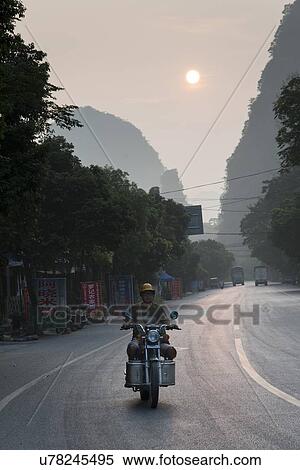 Man riding a motorcycle on the road, Yangshuo, Guilin, Guangxi Province, China View Large Photo Image Stock Photography - Man riding a motorcycle on the road, Yangshuo, Guilin, Guangxi Province, China. Fotosearch