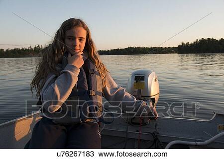 Stock Image - Portrait of a girl sitting in a boat and thinking, Lake of The Woods, Ontario, Canada. Fotosearch