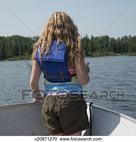 Stock Image - Rear view of a girl enjoying in a boat, Lake of The Woods, Keewatin, Ontario, Canada. Fotosearch