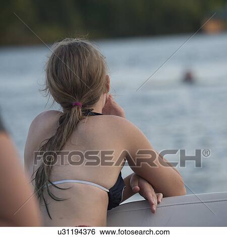 Stock Photograph - Rear view of a woman enjoying in a boat, Lake of The Woods, Keewatin, Ontario, Canada. Fotosearch