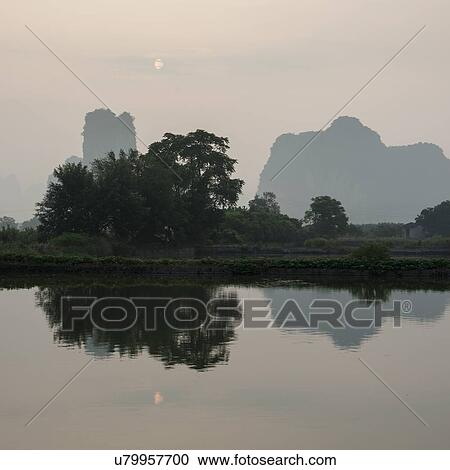 Stock Image - Reflection of trees on Yulong River, Yangshuo, Guilin, Guangxi Province, China. Fotosearch