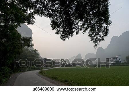 Road passing through a field, Yangshuo, Guilin, Guangxi Province, China View Large Photo Image Stock Photograph - Road passing through a field, Yangshuo, Guilin, Guangxi Province, China. Fotosearch