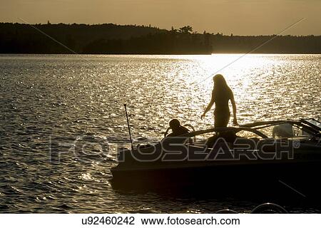 Silhouette of two people on a motorboat at sunset, Lake of The Woods, Keewatin, Ontario, Canada View Large Photo Image Stock Image - Silhouette of two people on a motorboat at sunset, Lake of The Woods, Keewatin, Ontario, Canada. Fotosearch