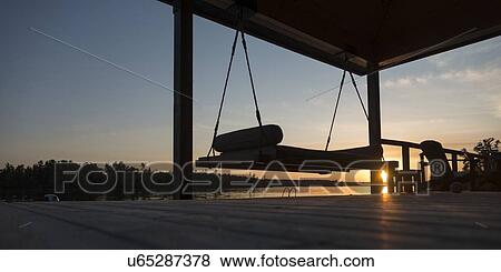 Stock Photo - Swing chair on a dock at sunset, Lake Of The Woods, Keewatin, Ontario, Canada. Fotosearch