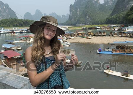 Stock Photo - Teenage girl holding a Chinese yuan note at riverside, Li River, Xingping, Yangshuo, Guilin, Guangxi Province, China. Fotosearch