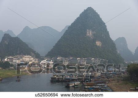 Picture - Tourboats in the Li River with a town at the waterfront, Yangshuo, Guilin, Guangxi Province, China. Fotosearch