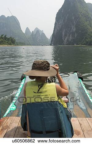 Stock Image - Tourist on a raft in Li River, Yangshuo, Guilin, Guangxi Province, China. Fotosearch