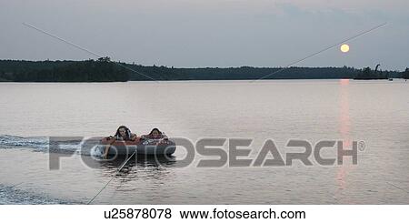 Stock Photo - Tourists being pulled on an inflatable raft floating on water, Lake of The Woods, Keewatin, Ontario, Canada. Fotosearch
