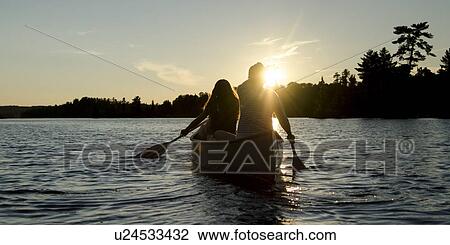 Stock Image - Tourists boating in the lake at sunset, Lake Of The Woods, Keewatin, Ontario, Canada. Fotosearch