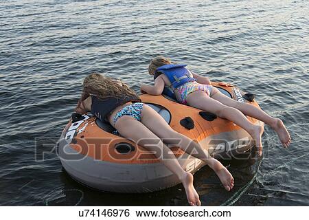 Two girls lying on an inflatable raft floating on water, Lake of The Woods, Ontario, Canada View Large Photo Image Stock Photograph - Two girls lying on an inflatable raft floating on water, Lake of The Woods, Ontario, Canada. Fotosearch