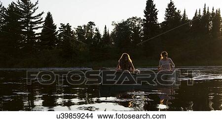 Picture - Two girls rowing a boat in a lake, Lake of The Woods, Ontario, Canada. Fotosearch