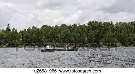 Stock Photograph - Two girls rowing a boat in a lake, Lake of The Woods, Ontario, Canada. Fotosearch