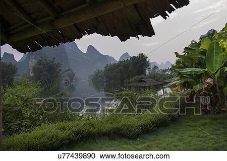 Stock Image - View of a river with mountains in the background, Yangshuo Mountain Retreat, Yangshuo, Guilin, Guangxi Province, China. Fotosearch