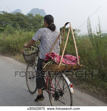 Woman cycling on the road, Yangshuo, Guilin, Guangxi Province, China View Large Photo Image Stock Photography - Woman cycling on the road, Yangshuo, Guilin, Guangxi Province, China. Fotosearch