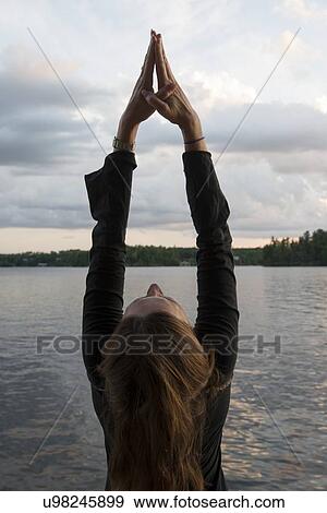 Stock Photo - Woman doing yoga at the lakeside, Lake of The Woods, Keewatin, Ontario, Canada. Fotosearch