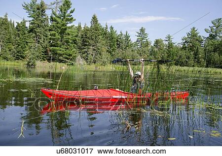 Stock Photo - Woman kayaking in a lake, Lake of The Woods, Keewatin, Ontario, Canada. Fotosearch