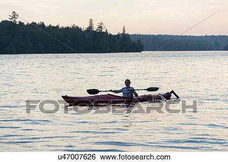 Stock Photograph - Woman kayaking in a lake, Lake of The Woods, Keewatin, Ontario, Canada. Fotosearch