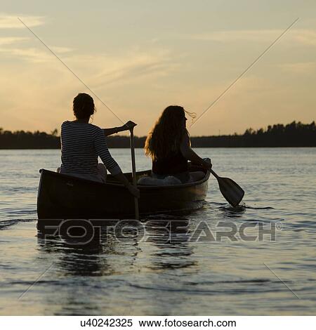 Stock Photography - Woman rowing a boat with her daughter at sunset, Lake of The Woods, Keewatin, Ontario, Canada. Fotosearch
