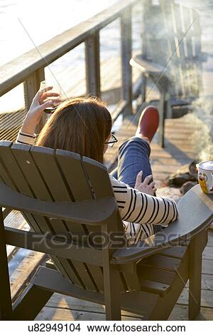 Picture - Woman sitting in an adirondack chair, Lake of The Woods, Keewatin, Ontario, Canada. Fotosearch